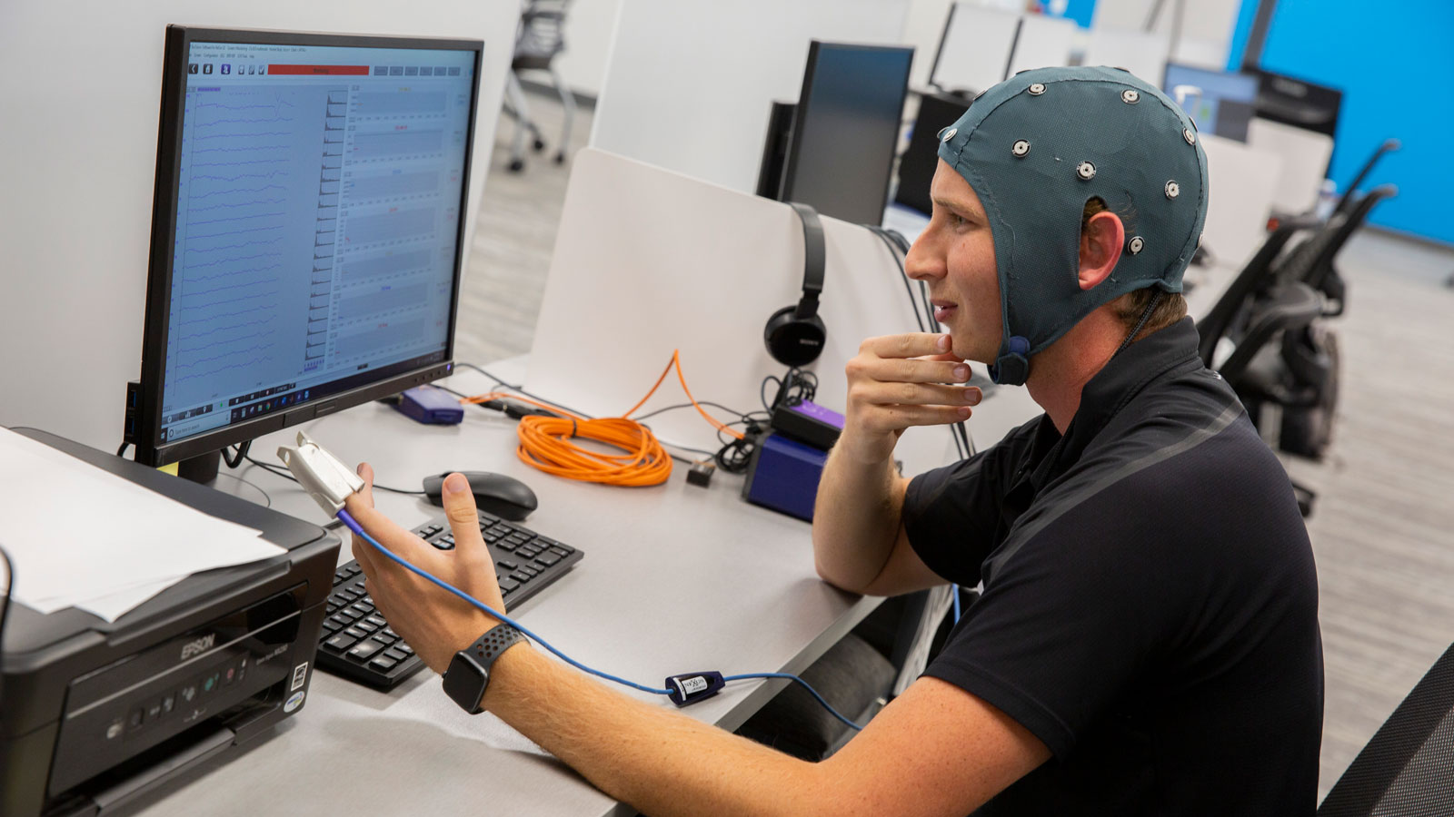Nick Hool demonstrates the clinical study Hoolest uses to gather data about the investigational non-invasive vagus nerve stimulation device in the WearTech Applied Research Center.