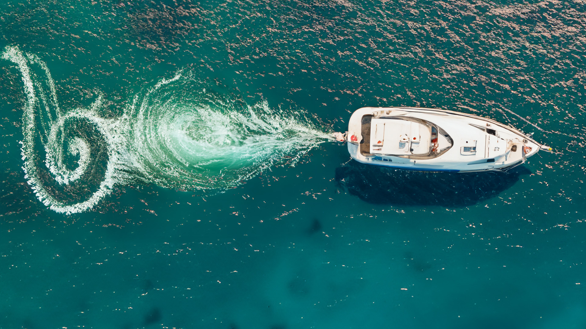 overhead view of a boat on with a swirl pattern behind it